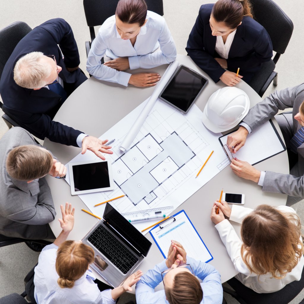 construction business, architecture and building concept - group of architects with laptop computer discussing blueprint at office