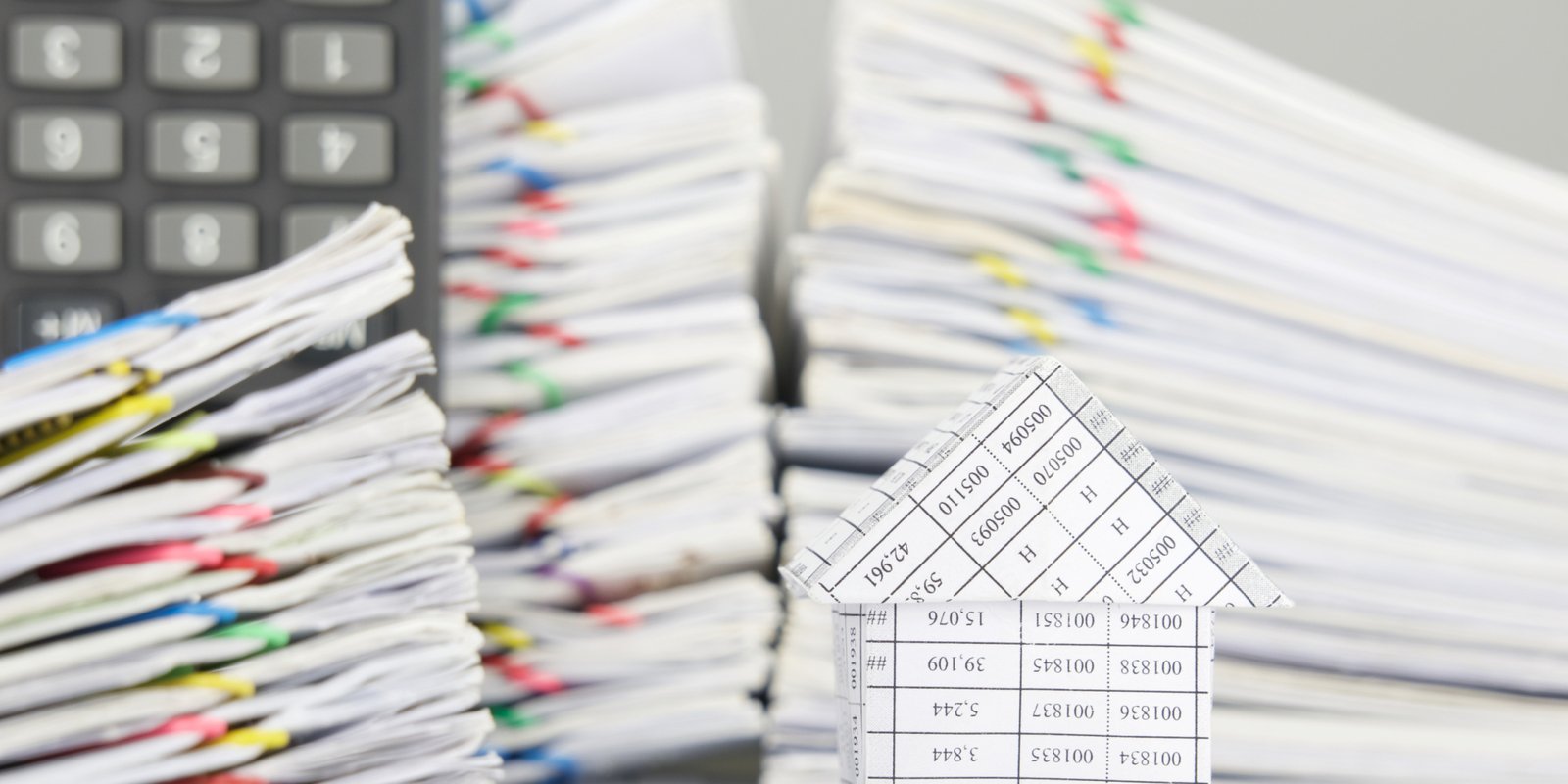 House on finance account have blur pile overload document of report and receipt with colorful paperclip and calculator place vertical as foreground and background.